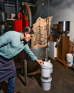 Altura Coffee - coffee roaster reaching for a bucket