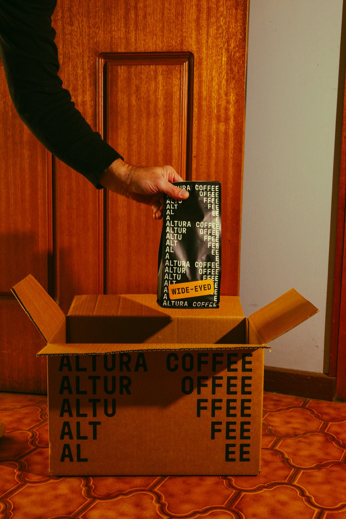 A bag of Altura Coffee Wide-Eyed espresso blend being packed into an Altura delivery box